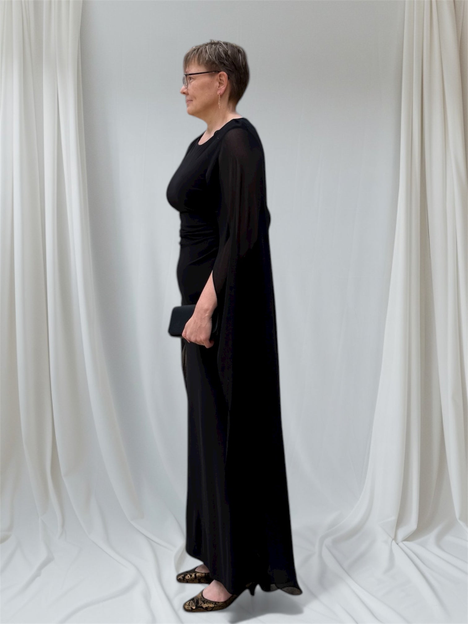 Sivukuva tyylikkäästä pelkistetystä iltapuusta. Sifonkiviitta peittää käsivarret.